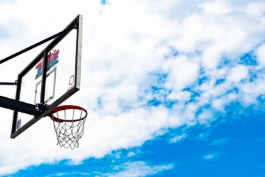 Bulutlu mavi gökyüzünün üzerinde basketbol tahtası, şehirde sokak basketbolu