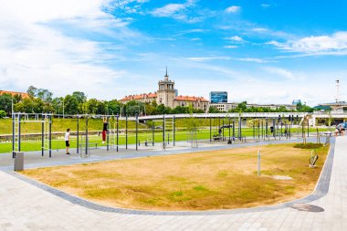 Vilnius, Litvanya - 3 Temmuz 2020: İnsanlar arka planda mavi gökyüzü ve şehirle birlikte parktaki açık hava spor salonunda egzersiz yapıyorlar