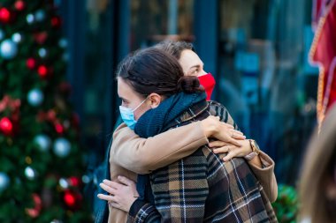 Vilnius, Litvanya - 11 Kasım 2020: Covid ya da Coronavirus salgını sırasında maskeli kızlar, toplantı ve kucaklaşma, Noel arkaplanı, kucaklaşma, aşk konsepti