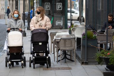Vilnius, Litvanya - 6 Kasım 2020: Bebek arabalı kızlar Covid veya Coronavirus salgını sırasında alışveriş merkezi yakınlarında geziyorlar