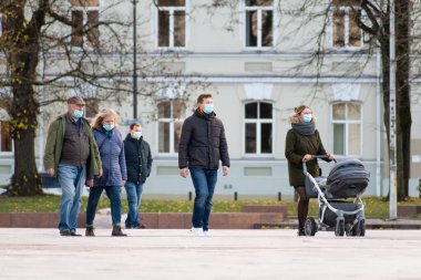 Vilnius, Litvanya - 6 Kasım 2020: Covid veya Coronavirus salgını sırasında şehirde bir dükkan veya alışveriş merkezi yakınında yürüyen bebek arabalı aile