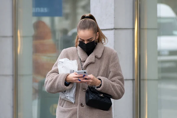 Vilnius, Litvanya - 6 Kasım 2020: Covid ya da Coronavirus acil durumu sırasında akıllı telefondan uygulamayı kontrol eden maskeli kız ya da kadın. 
