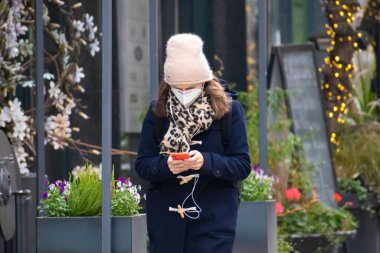 Vilnius, Litvanya - 10 Kasım 2020: Uygulamayı kontrol eden maskeli güzel bir kız Covid ya da Coronavirus acil durumu sırasında akıllı telefondan Covid 'i durdurun, uygulamayı takip edin, takip edin 