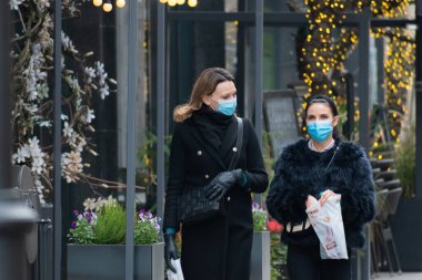 Vilnius, Litvanya - 10 Kasım 2020: Covid veya Coronavirus salgını sırasında alışveriş için maske takan ve şehirde yürüyen güzel bir kız