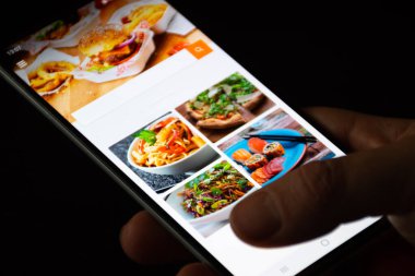 Vilnius, Litvanya - 18 Kasım 2020: gıda siparişi ve teslimat servisi. Covid ya da Coronavirus salgını sırasında atıştırmalık yemek, akıllı telefon uygulaması parmaklarıyla çeşitli yiyecekleri, pizzayı, makarnayı, suşiyi, fast food 'u gösteren uygulama.