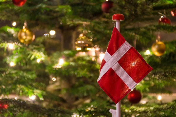 Danimarka bayrağı, İskandinav kandili, süsleri ve ışıkları, Noel süslemeleri ve arka planı olan güzel bir Noel ağacı.
