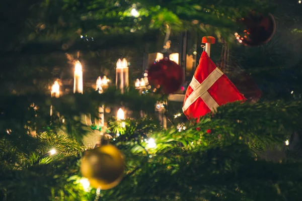 Danimarka bayrağı, İskandinav kandili, süsleri ve ışıkları, Noel süslemeleri ve arka planı olan güzel bir Noel ağacı.