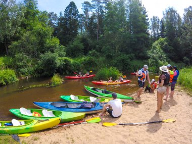 Litvanya 'da kano gezisi, kano manzarası, sahilde bekleyen insanlar ve nehirde kano süren insanlar.