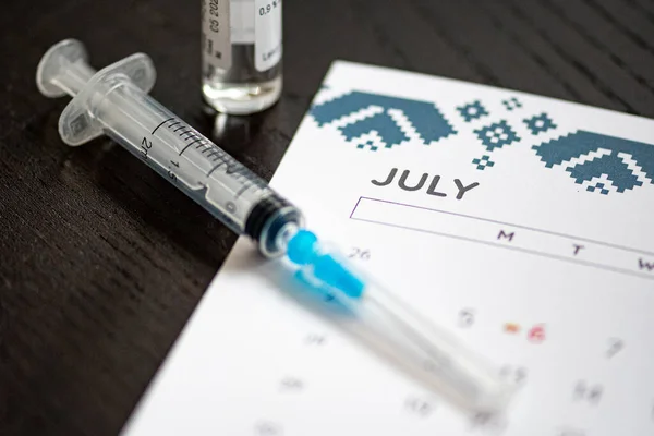 使用する準備ができて黒のテーブルの上に7月の月と神社 バイアルとカレンダー コヴィドワクチンまたはコロナウイルスワクチンの背景 — ストック写真