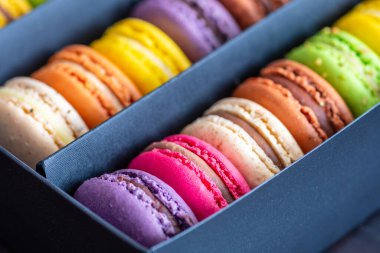 Bir hediye kutusundaki çeşitli renkli badem kurabiyeleri veya Fransız kurabiyeleri, yumurta beyazı, krema şekeri, granüllü şeker, badem yemeği ve gıda boyasıyla yapılan tatlı krema bazlı şekerlemeler, yakın plan.