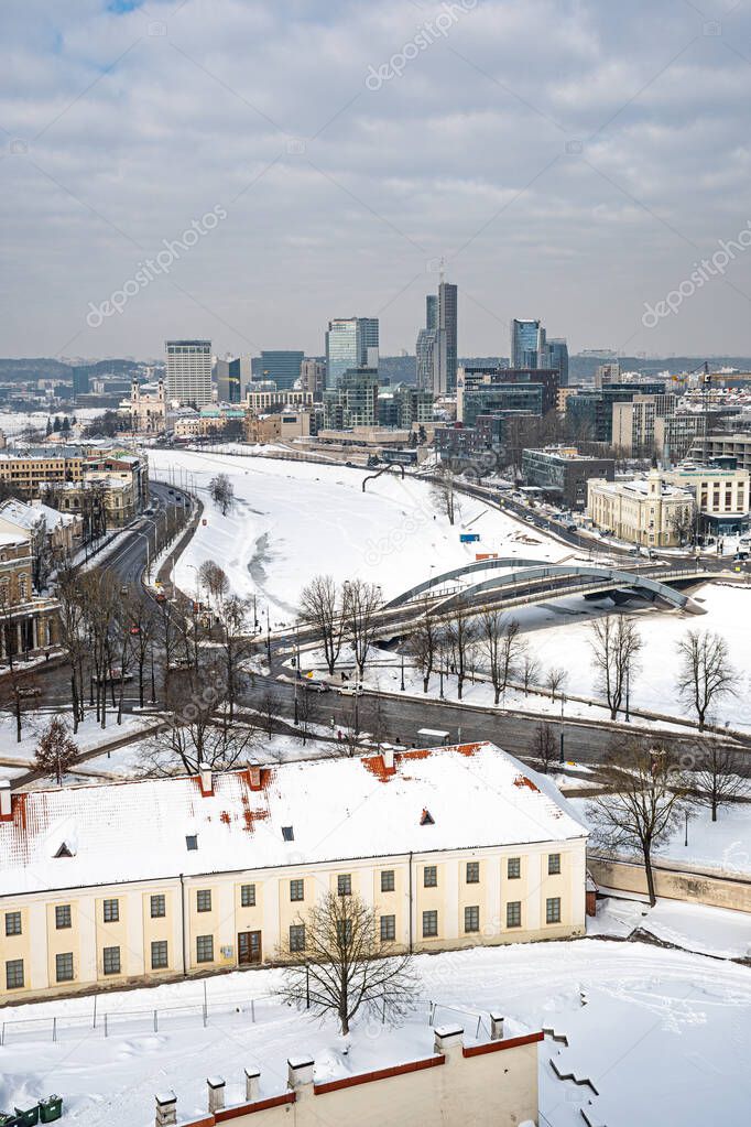 Vilnius, capital of Lithuania, beautiful scenic aerial panorama of modern business financial district architecture buildings with snow, Neris river and bridge, vertical