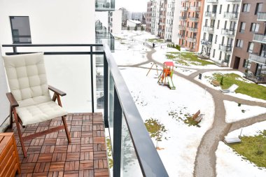 Modern minimalist mimari ve binaları bloklar, kışın bahçeli ve oyun parklı mikro bölge, balkondan sandalye ve ahşap zemin manzarası