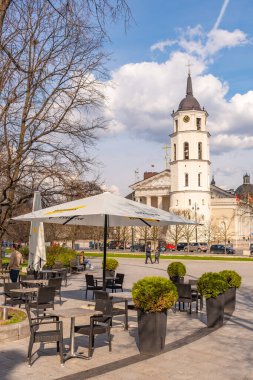 Vilnius, Litvanya - 21 Nisan 2021: Vilnius, Covid veya Coronavirus, masa, sandalye ve şemsiyeler nedeniyle arka planda Katedral Kulesi, dikey