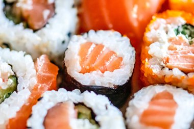 Çeşitli suşiler yiyorum. Maki, uramaki, hosomaki, sahimi ve nigiri ruloları bir tabakta, kompozisyonu kapat.