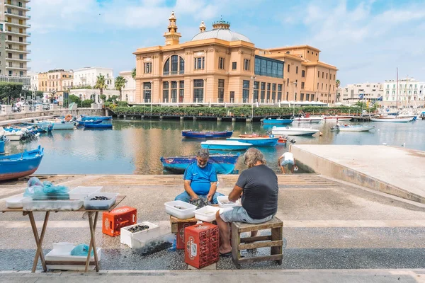 Bari, İtalya - 26 Ağustos 2021: Yerel balıkçılar, Bari gezinti alanı, Puglia, İtalya 'daki bir açık hava sokak gıda pazarında taze deniz ürünlerini temizleyip satmaya hazır hale geldiler