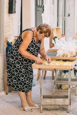 Bari, İtalya - 27 Ağustos 2021: Bari eski kasaba orkestrası veya orecchietta caddesinde hazırlanan yerel yaşlı kadın, buğday ve suyla yapıldı, el yapımı makarna Puglia 'nın tipik dikey