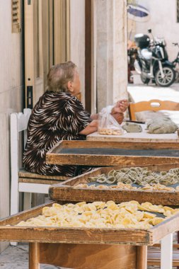 Bari, İtalya - 27 Ağustos 2021: Bari eski kasaba orkestrası veya orecchietta sokaklarında satılan yerel yaşlı kadın, buğday ve suyla yapıldı, el yapımı makarna tipik Puglia veya Apulia, dikey