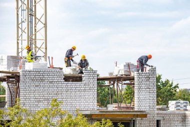 Vilnius, Litvanya - 28 Eylül 2021: Bulutlu gökyüzüne karşı çalışan işçilerle birlikte yeni binalar veya inşaat halindeki evler