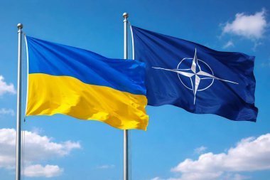 Ukrayna ve NATO bayrakları açık mavi gökyüzüne karşı yan yana dalgalanıyor, ortaklığı, dayanışmayı ve uluslararası işbirliğini simgeliyor