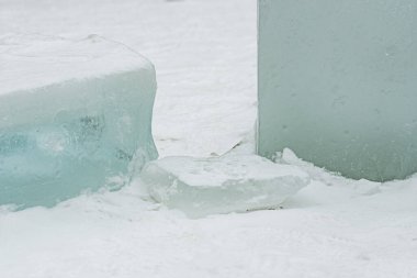 Taze beyaz kar üzerinde dinlenen şeffaf buz bloklarının yer aldığı soyut kış sahnesi, donmuş dokular, serin tonlamalar ve soğuk açık havada minimalist doğal formlar sergiliyor.