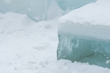 Taze beyaz kar üzerinde dinlenen şeffaf buz bloklarının yer aldığı soyut kış sahnesi, donmuş dokular, serin tonlamalar ve soğuk açık havada minimalist doğal formlar sergiliyor.