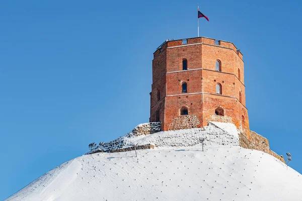 Gediminas Kulesi ya da Kalesi, kar, Vilnius, Litvanya 'nın Litvanya bayrağıyla kaplı tepedeki Yukarı Ortaçağ Kalesi' nin kalan kısmı güneşli bir kış günü