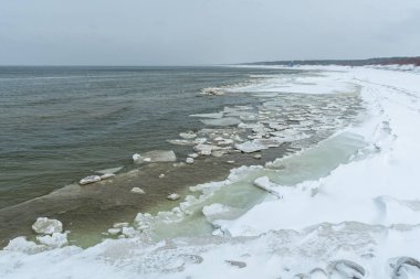 Donmuş dalgalarla dondurucu kış deniz manzarası, Litvanya 'nın Palanga kentindeki Baltık Denizi' nde karlı bir kıyı şeridi boyunca yüzen buzlar.