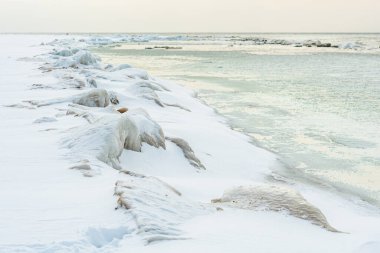 Donmuş dalgalarla dondurucu kış deniz manzarası, Litvanya 'nın Palanga kentindeki Baltık Denizi' nde karlı bir kıyı şeridi boyunca yüzen buzlar.