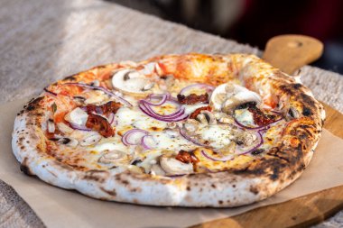 Domates soslu sıcak pizza, taze mozzarella peyniri, mantar ve ahşap tahtada kırmızı soğan.