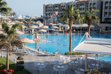 Ağaçlarla ve farklı renkte süslü çalılarla, desenli dekoratif yapraklarla her zaman yeşil yüzme havuzlarının ve doğu tarzında binaların yanında