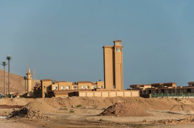 Sahra Çölü 'nün Mısır bölgesinde, gri, turuncu veya kahverengi tonlarında boyanmış cephelerle beton, tuğla ya da granitten yapılmış doğu mimarisi binaları ile görüntülenir 