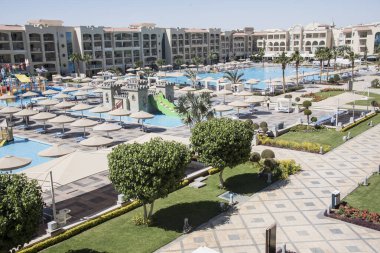 Süslü çalılar-Hurghada-Mısır çeşitli şekillerde parlak renklerde, havuz kenarındaki yeşil desenli yapraklar ve doğu tarzı binalar 