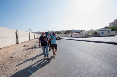Hurghada-Mısır 'daki turist, açık renkli yaz kıyafetlerine karşı koruyucu bir maskeyle yürüyor 