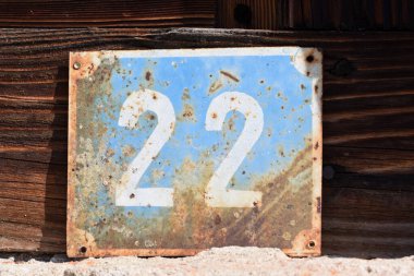 Eski ahşap dokunun arka planına uygulanan mavi arka planda beyaz plakalı metal plaka 
