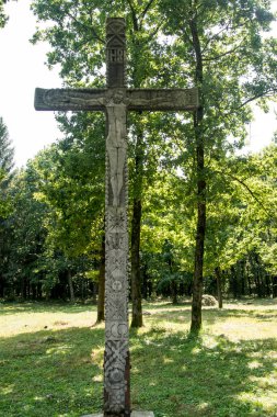 Yolun kenarındaki haç, ortodoks haç ve güneş rozetlerinin baskın olduğu motiflerle tahtadan oyulmuştur. Kötü ruhları uzak tutmak için çatal ve yol kesişimlerinde bulunur.