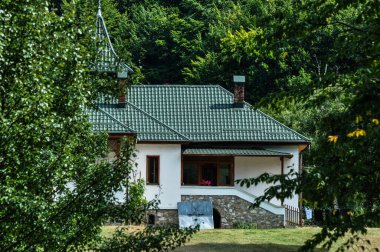 Yeşil çayır manzarası, farklı özlerden ağaçlarla dolu bir orman ve Prislop Manastırı 'ndaki rahibelerin evi için bir hücre. 