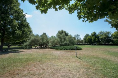 Egzotik ağaçları olan Infinity Sütun Parkı, sütun erişim sokağı, turist bankları ve iyi bakımlı çimenlikleri