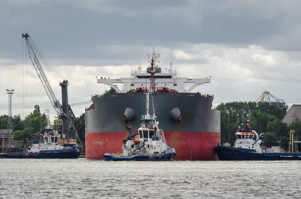 MARITIME TRANSPORT - A bulk carrier is maneuvering in a seaport assisted by tugs