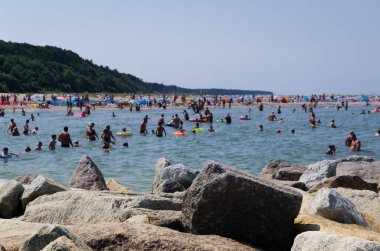 Yazın Deniz Kıyısı - Taşlar kıyıları güçlendiriyor ve tatilciler deniz suyunda dinleniyor