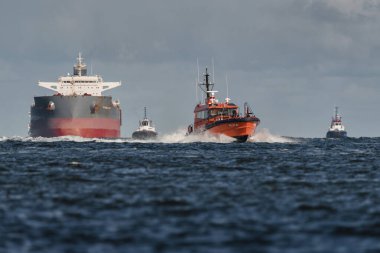 SUÇLU, BATI POLAND - 23 Eylül 2025: MARITIME TRANSORT - Pilot tekne, römorkörler ve gemi limana doğru yelken açıyor