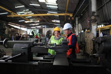 Makineli Erkek ve Kadın Endüstri Mühendisleri. Endüstride üretim mühendisine yardım. Bir plastik fabrikasında, endüstriyel metalleri kontrol ediyor ya da itiyor. Çalışma Konsepti Başarılı.