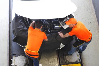 Araba tamircisi, sanayinin motor tamirinden motor tamirine, otomobil taşımacılığı otomobili ve üst görünüm görüntü bakımını kontrol etmek için dizüstü bilgisayar kullanır 