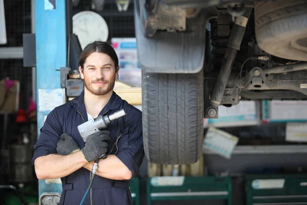 Portrait of a mechanic at work in his garage or car repair service or auto store, business, maintenance and people concept