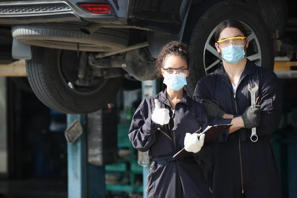 two car mechanic on protective mask anti coronavirus or covid19 ,  they are fixing  and service maintenance of industrial to engine repair, for transport automobile automotive
