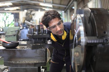 Fabrika mühendisi büyük makine çalıştırıyor. Endüstri konsepti için malzemeyi kesti. 