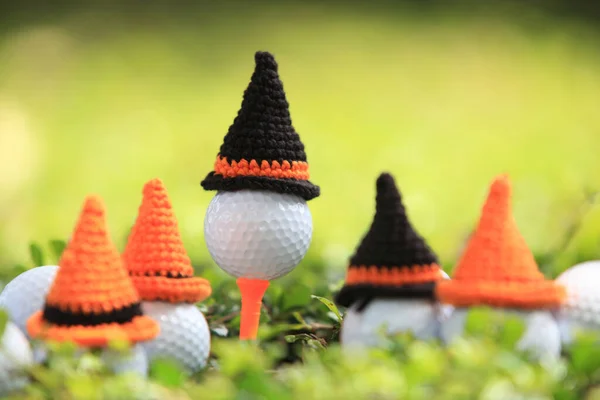 ゴルフコースの背景のホリデーシーズンのコンセプトのためのハロウィンの帽子とティーの上のゴルフボール — ストック写真