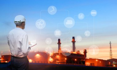 Bir adam, fabrika endüstrisi 4.0 konsepti olan ağır sanayi arka planındaki petrol rafinerisini izliyor. 
