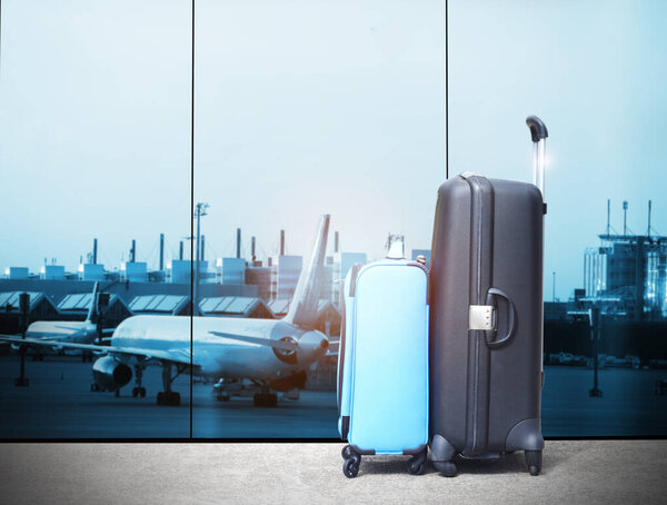 traveler suitcases in airport terminal waiting area,  interior with large windows, focus on bag,summer vacation concept, airplane in background,