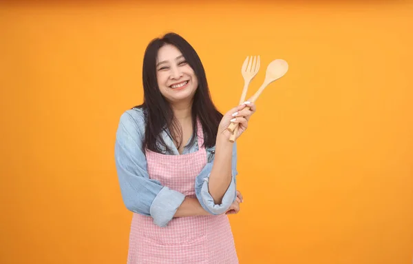 아시아인 여성이 노란색 배경에 주제를 광고하기 앞치마로 요리를 — 스톡 사진