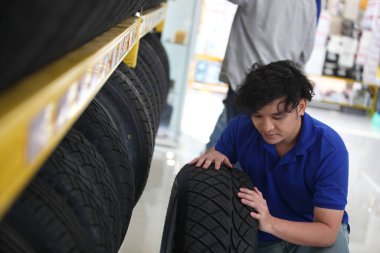 Araba tamirhanesinde veya araba tamirhanesinde tekerlek lastiklerini gösteren satıcı, iş yeri, bakım ve insan konsepti